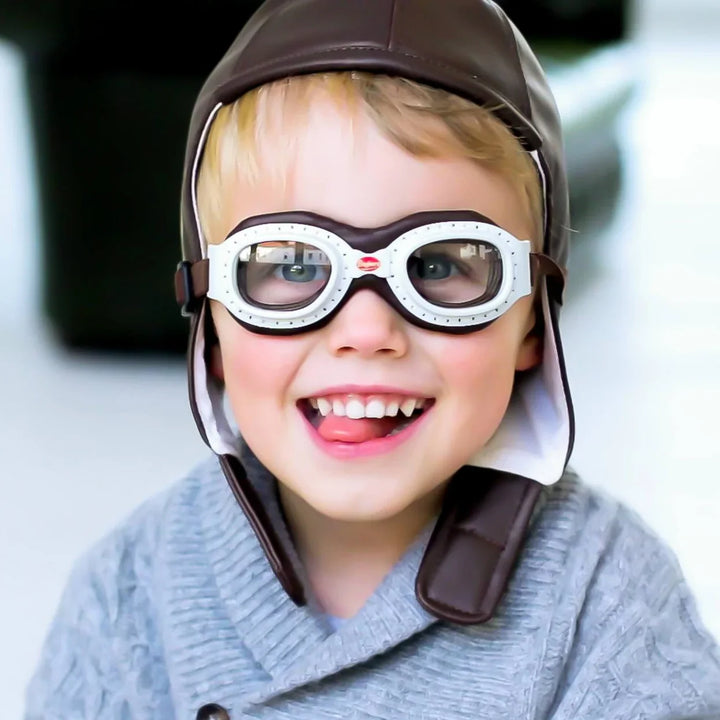 Child wearing a Baghera brown aviator helmet and goggles with a blurred background