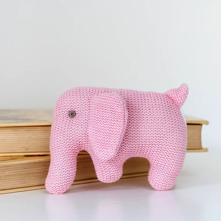Pink Best Years knitted organic cotton elephant baby rattle in front of books