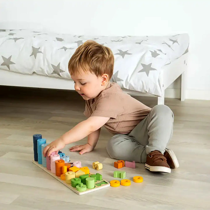 Child playing with a Bigjigs Toys 1-10 counting board on a wooden floor.