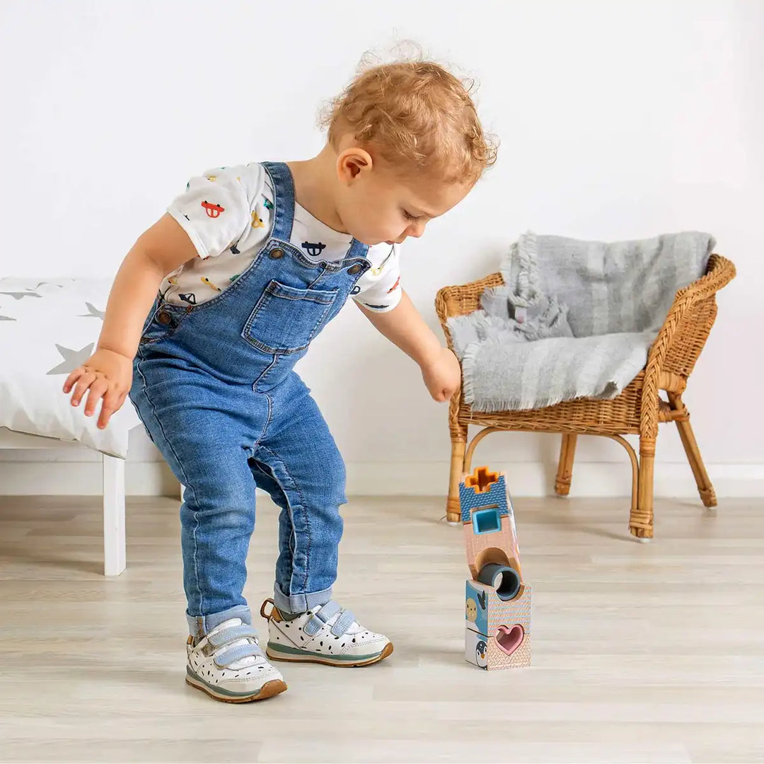 Child playing with a Bigjigs Toys arctic tower puzzle in a room with a chair and cushion.