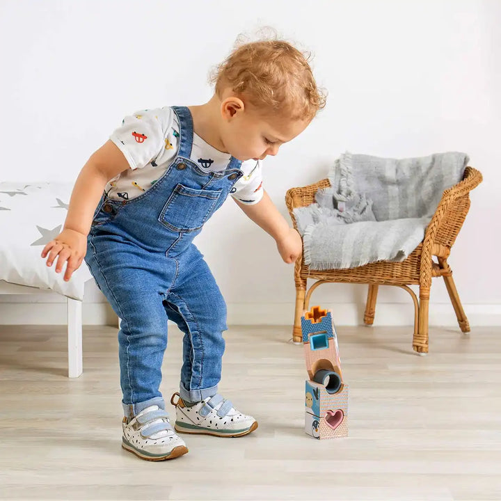Child playing with a Bigjigs Toys arctic tower puzzle in a room with a chair and cushion.