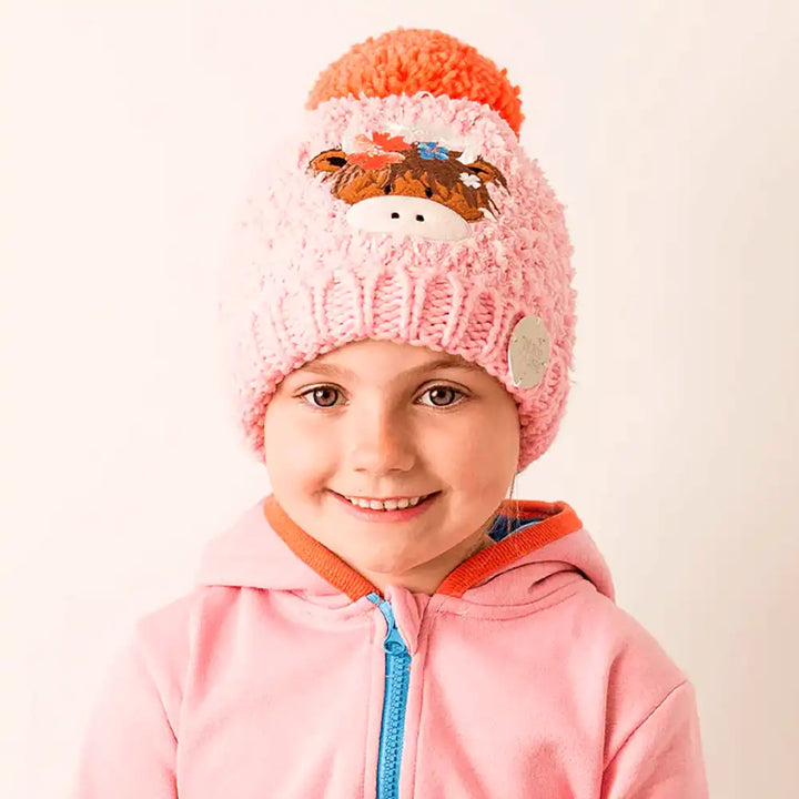 Child wearing a pink Blade & Rose Bonnie Highland Cow knit hat with a fox design on a beige background
