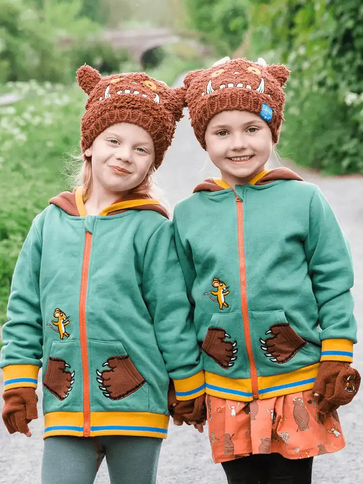 Children wearing a brown knitted Blade & Rose Gruffalo hat and mittens with a cartoon face design, outdoors.