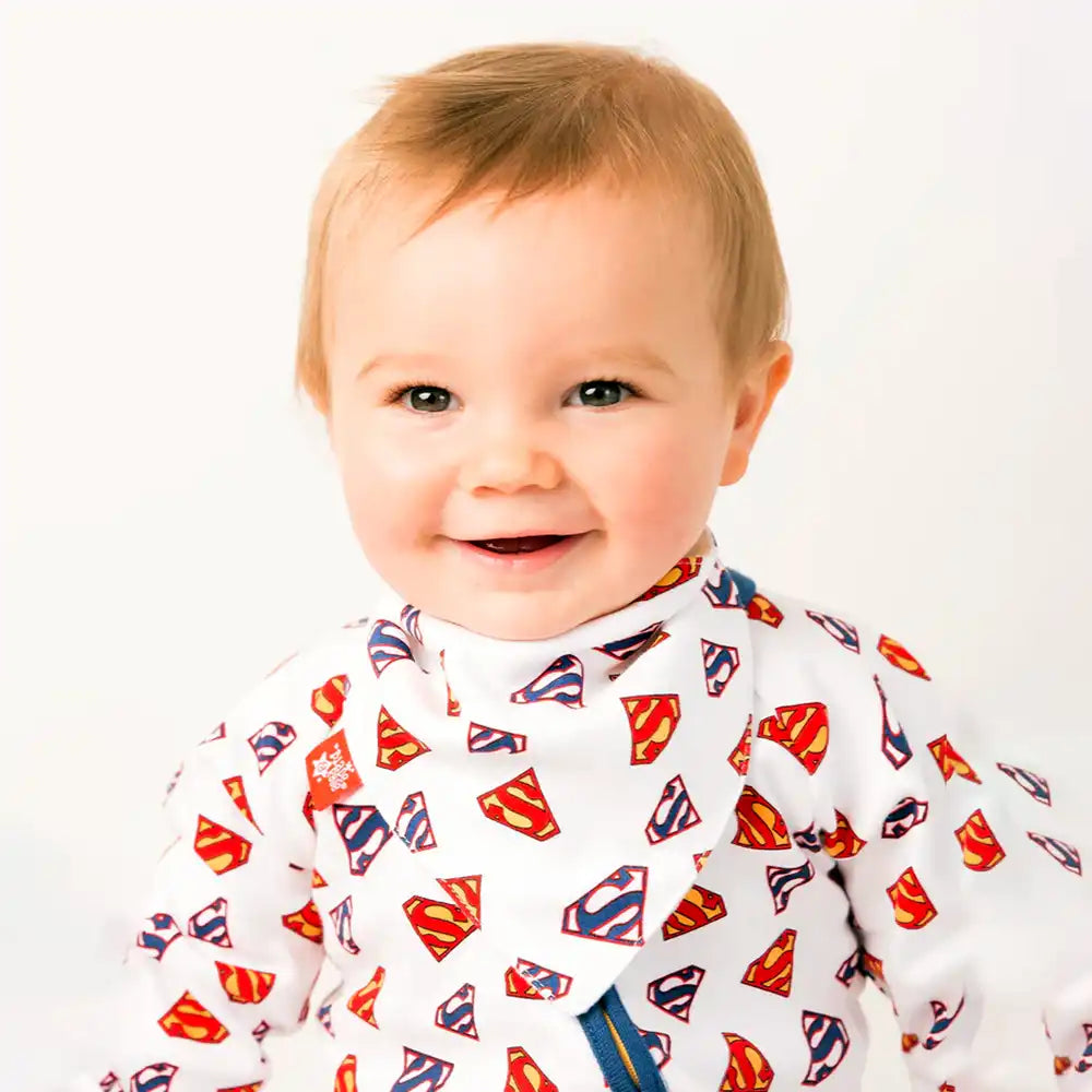 Baby wearing a Blade and Rose bib with Superman superhero's logos on a white background