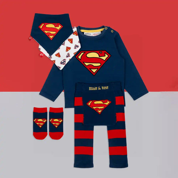 Blade and Rose Superman-themed baby outfit set with navy blue top, red shorts, socks, and bib on a red and gray background.