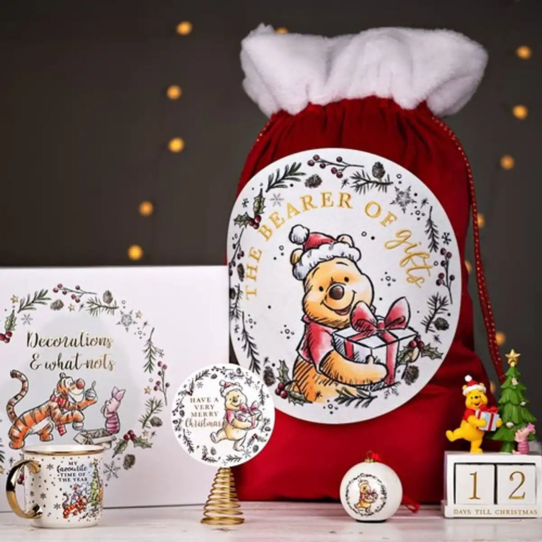 Red Christmas sack with Winnie the Pooh design, mug, and ornaments on a dark background.