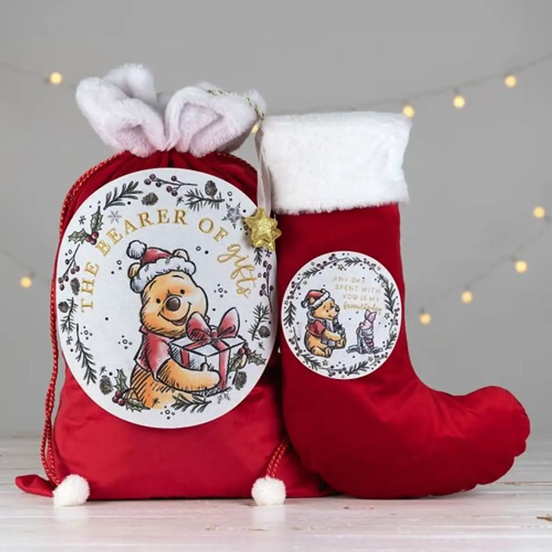 Red Christmas Winnie the Pooh stocking and drawstring bag with festive designs on a grey background.