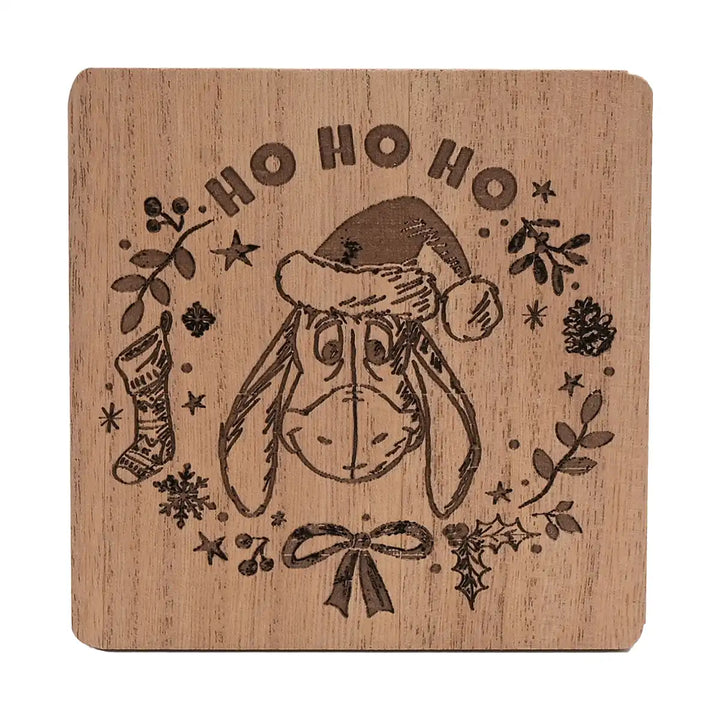 Disney Winnie the Pooh Christmas wooden coaster with Eeyore wearing a Santa hat, 'HO HO HO' text, and Christmas decorations.