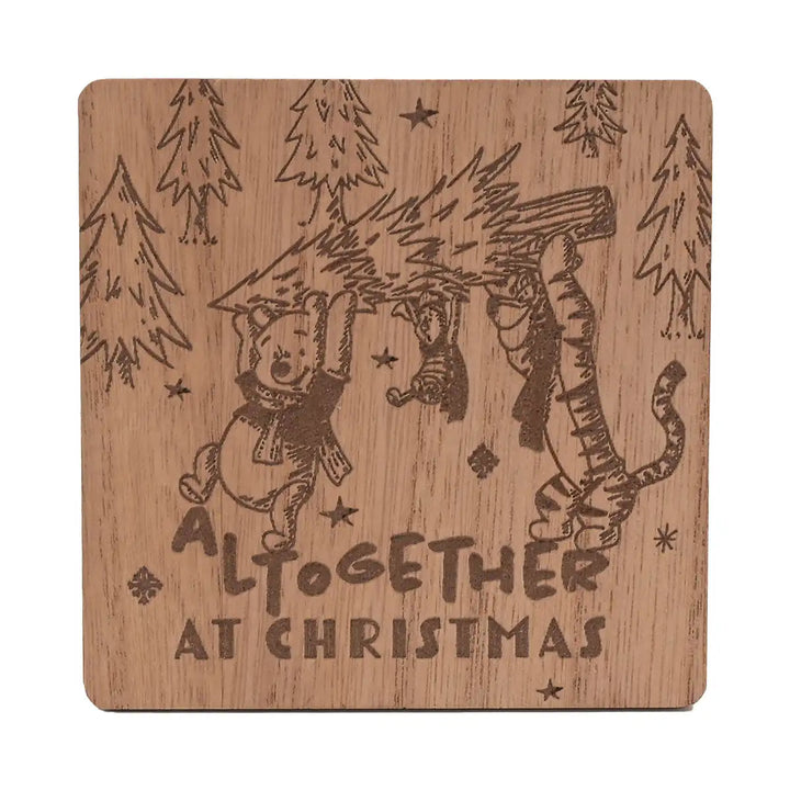 Winnie the Pooh Christmas wooden coaster with engraved illustration of Pooh, Piglet and Tigger under a Christmas tree, with 'ALtogether at Christmas' text.