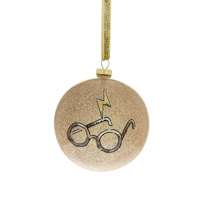 Round gold ornament with Harry Potter-themed design of glasses and a lightening bolt on a white background