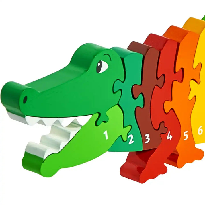 A Lanka Kade wooden puzzle crocodile toy with numbered pieces in a rainbow colour sequence from green to yellow, shown on a plain white background.