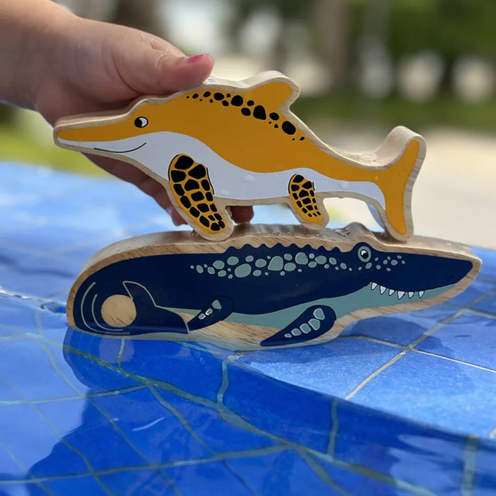 Lanka Kade wooden blue mosasaurus dinosaur figure, above a blue tiled surface outdoors. 