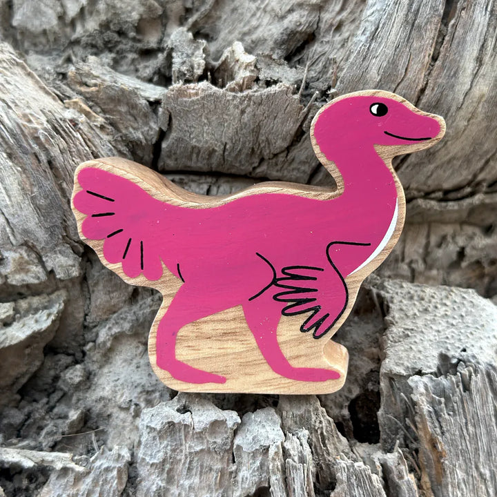 Lanka Kade wooden caudipteryx featuring a bright pink painted body with a natural wood-grain textured edge, displayed on a textured grey wood bark background.