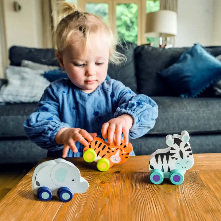 Child playing with Orange Tree Toys colourful first push animal wooden toys on a table