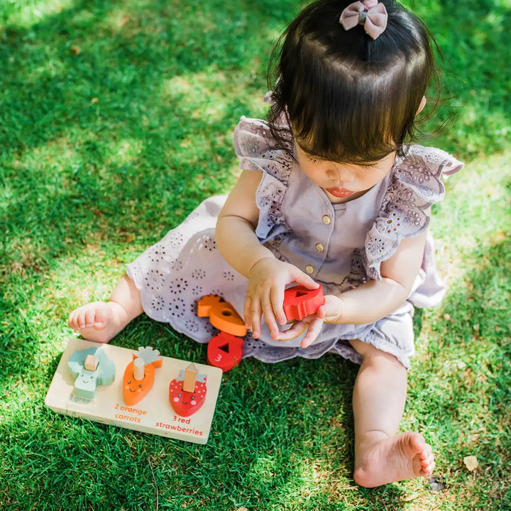 Child playing with an Orange Tree Toys counting veggies puzzle on grass