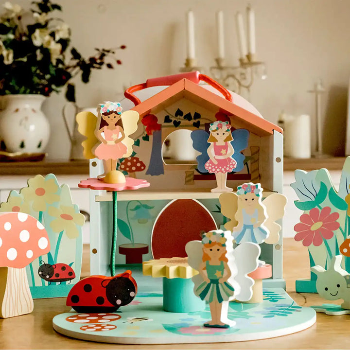 Orange Tree Toys wooden fairy house toy set with a small house and fairy figures on a decorative surface.