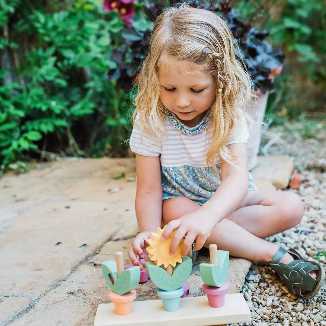 Young girl playing with Orange Tree Toys set of three wooden stacking flower pots