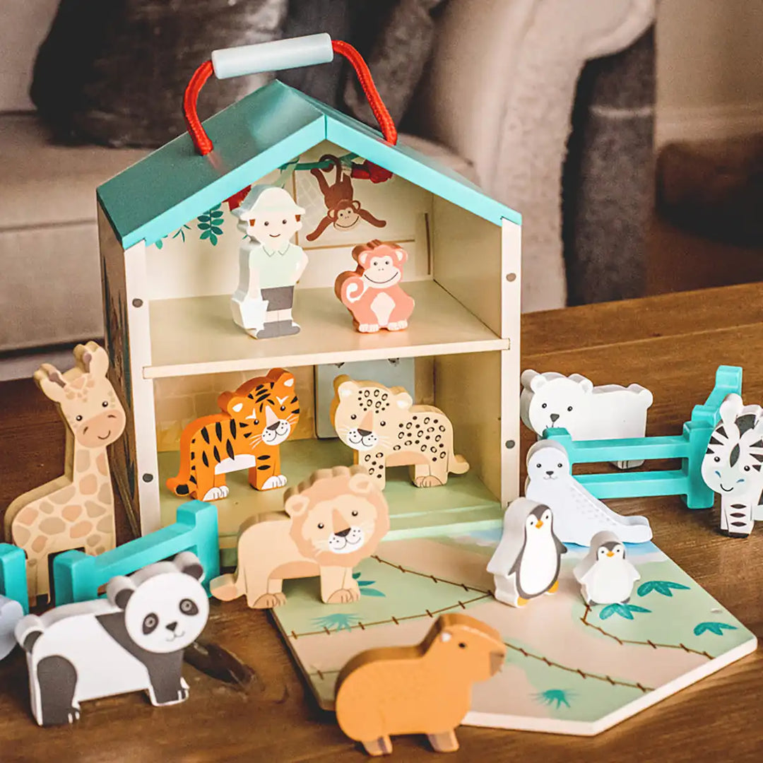 Orange Tree Toys zoo toy play set with a small playhouse structure on a wooden surface.