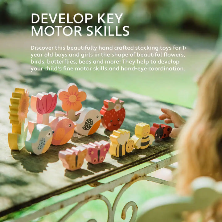 Orange Tree Toys stacking spring garden set shaped like flowers, birds, butterflies, and bees on a table with a child's hand reaching out.