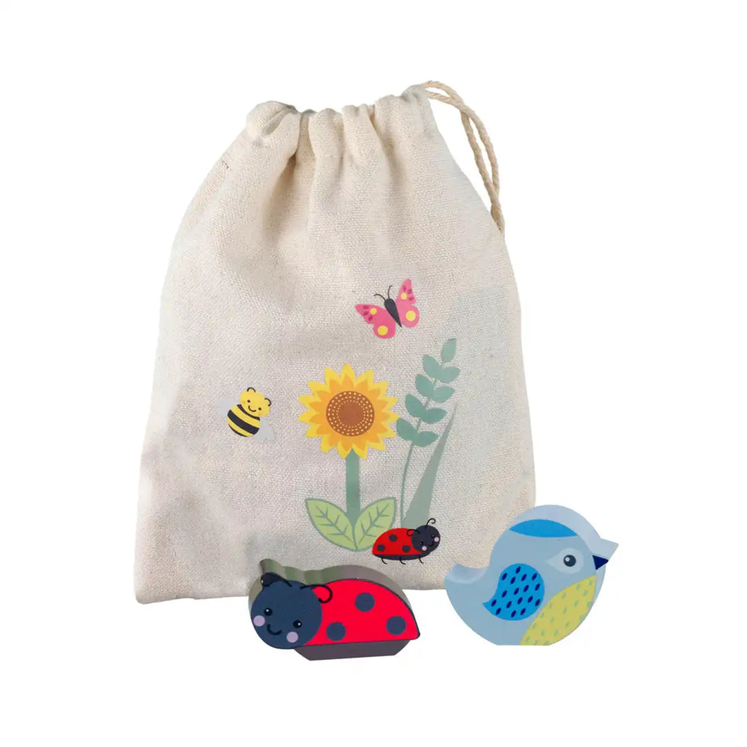 Orange Tree Toys stacking spring garden set drawstring bag with nature-themed design featuring a sunflower, butterfly, bee, ladybug, and bird, with wooden toys below on a white background.
