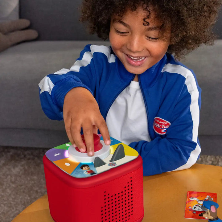Child playing with a a Tonies tonieplay controller in sunset red with a matching toniebox2 on a table