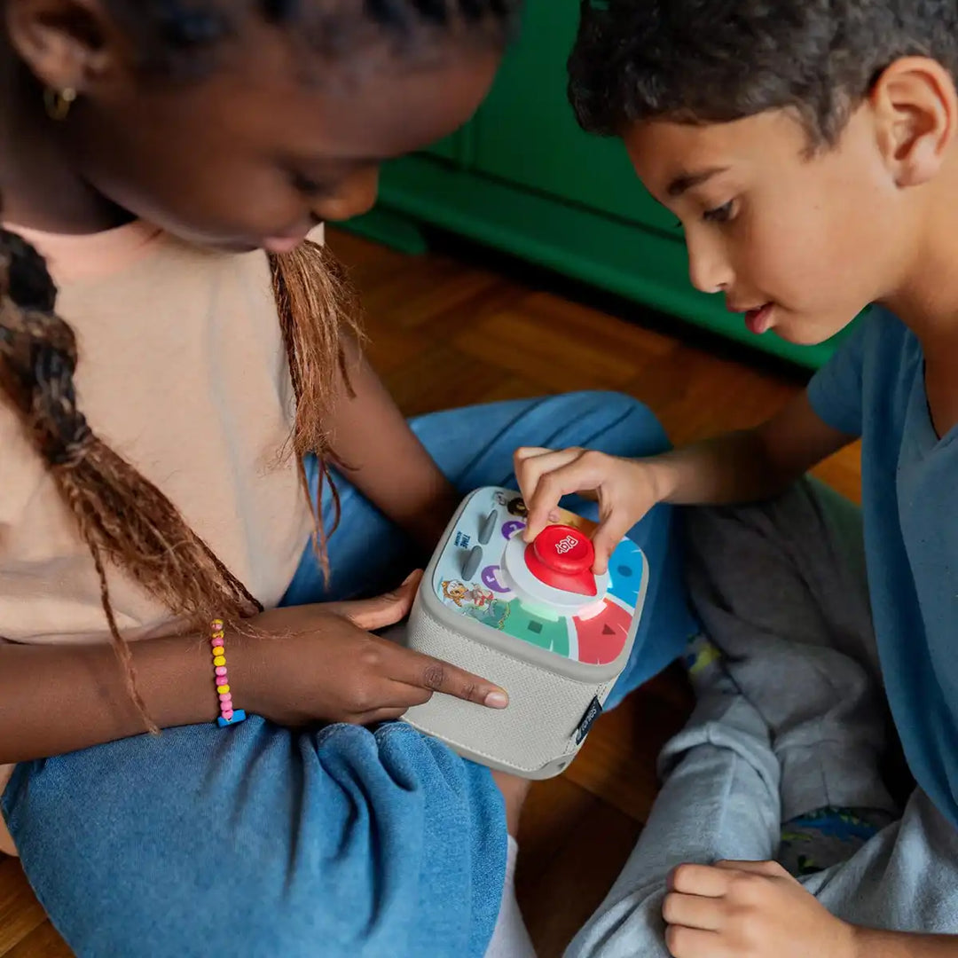 Two children playing with a colorful Tonieplay Time Academy game on a wooden floor.